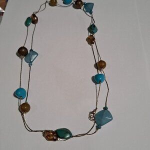 long silver color necklace with light brown tan blue turquoise colored beads